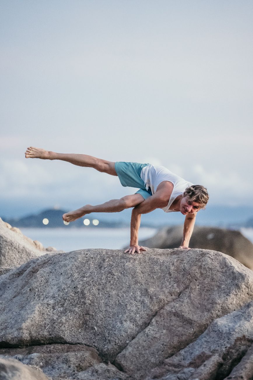 Boris Lauser in einer Yoga-Balance auf einem Felsen am Meer